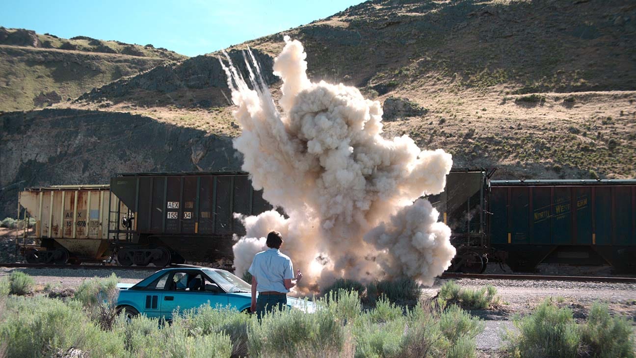 Man next to small car watching an explosion